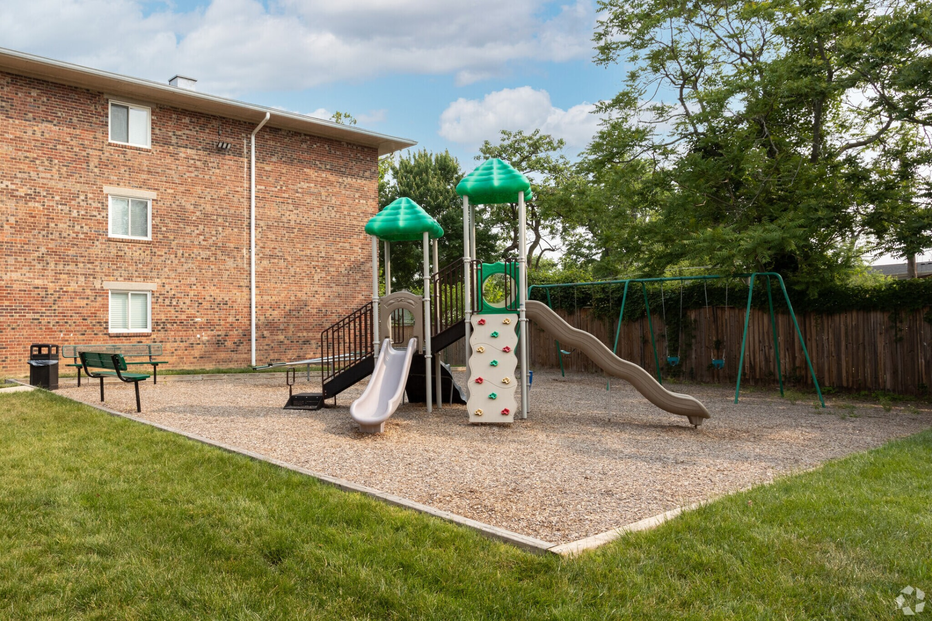 Playground with slides and swings beside a brick apartment building